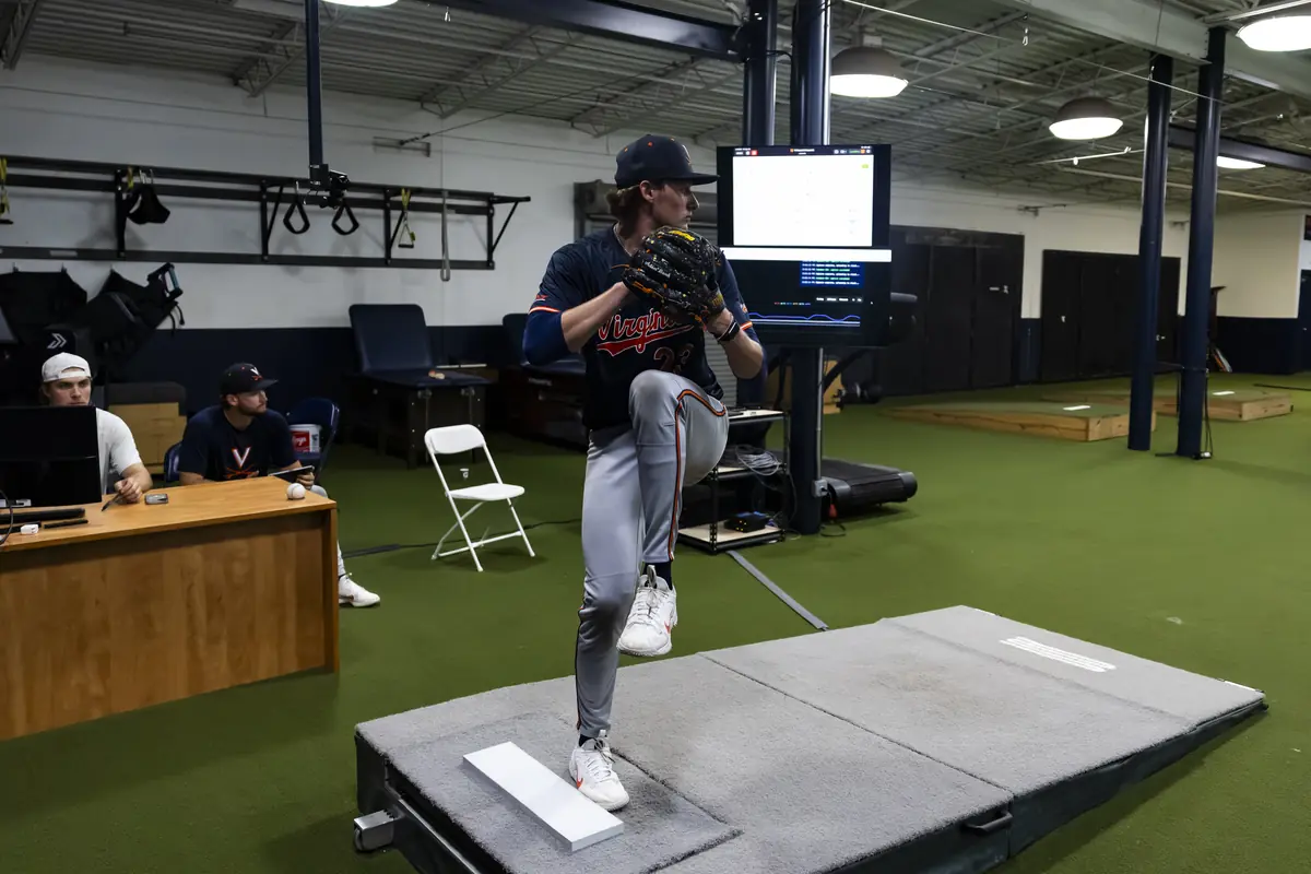 A Virginia pitcher on the mound beside assessment monitors inside the Virginia Maven Lab